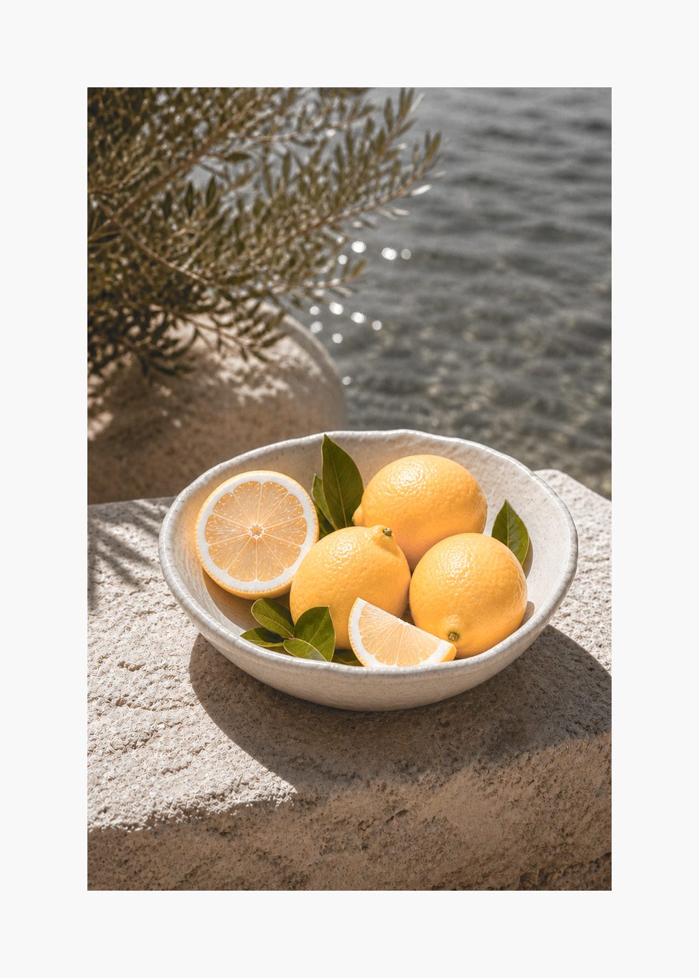 Citroner vid vattnet Poster med fräscha citroner i skål, omgiven av vatten och grönska, perfekt för kökstavlor.